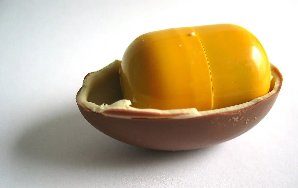 A halved Kinder Surprise chocolate egg, revealing a plastic cannister containing a toy.Image: Mysid.