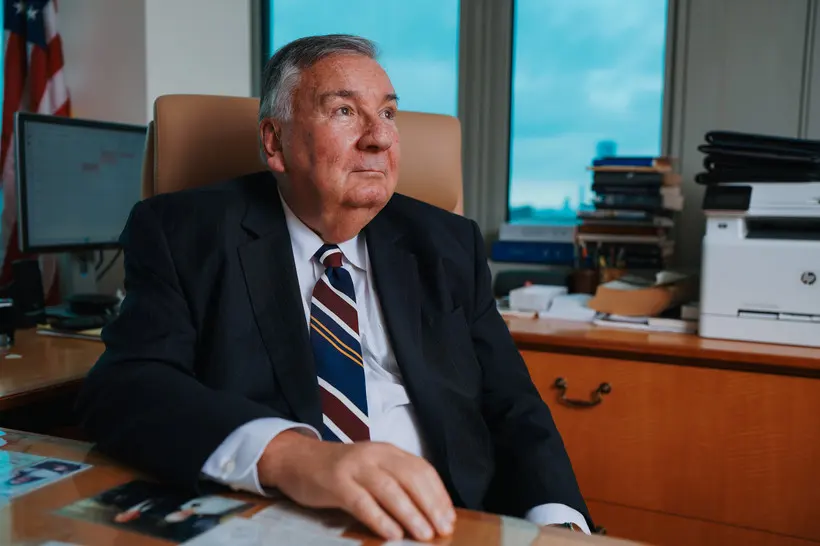 A man wearing a suit sitting at a desk in his office