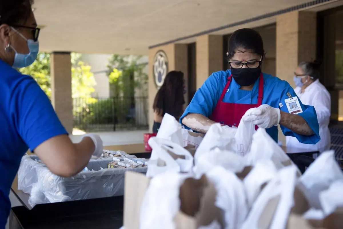 Round Rock ISD food service worker Hema Patel prepares meals for families during a curbside meal distribution at Bluebonnet Elementary School in Round Rock.