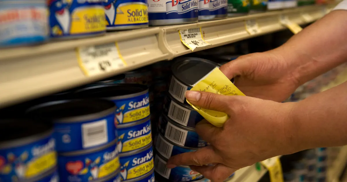 A person putting tuna cans on a grocery store shelf Credit: Amanda Voisard/The Washington Post via Getty Images via Sentient.