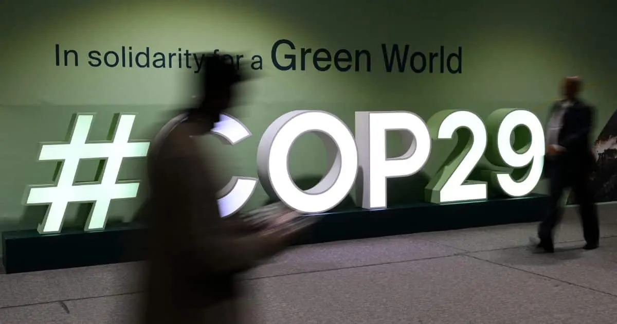 Attendees walk past the COP29 logo during the United Nations Climate Change Conference Credit: STRINGER/AFP via Getty Images via Sentient.