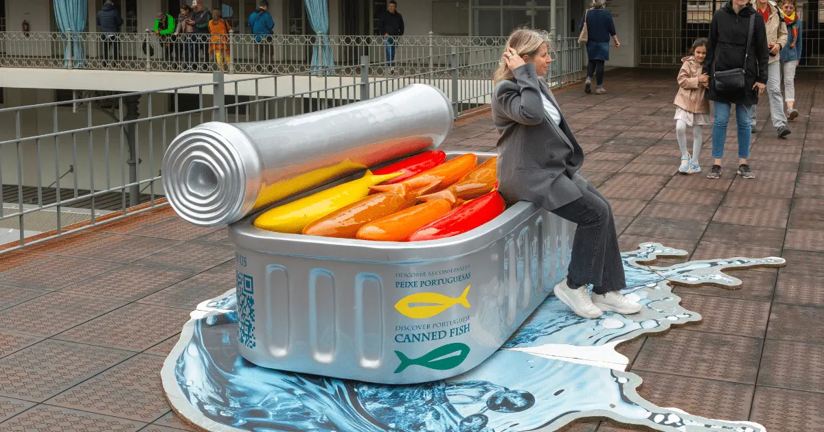 A woman sitting on a large art display of a tin of sardines Credit: Geography Photos/Universal Images Group via Getty Images via Sentient.